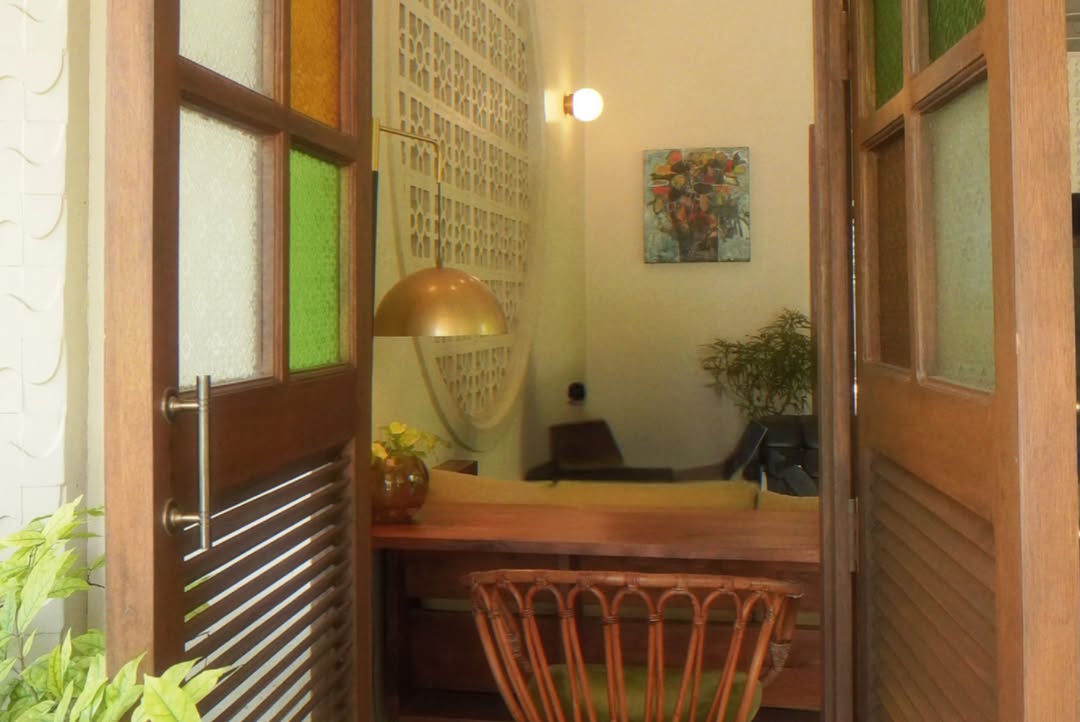 Reception nook with louvre door, brass globe lamp and original artwork